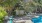 a swimming pool with chairs and a deck with trees and a fence